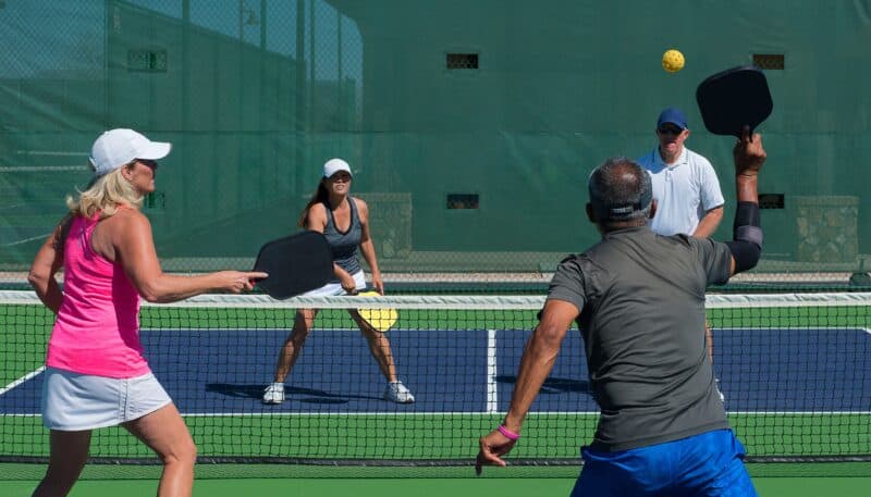 a group of people playing pickelball in teams of 2