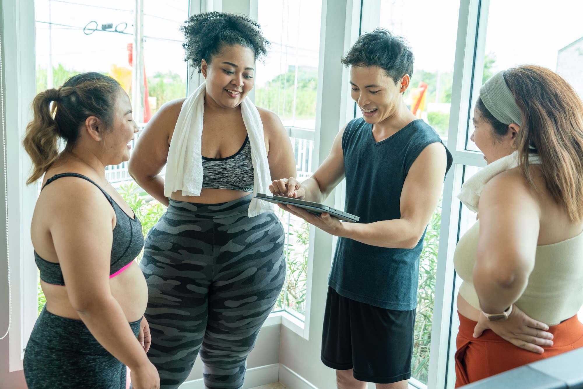 Fitness trainer guiding a client using club management software for tailored workouts.