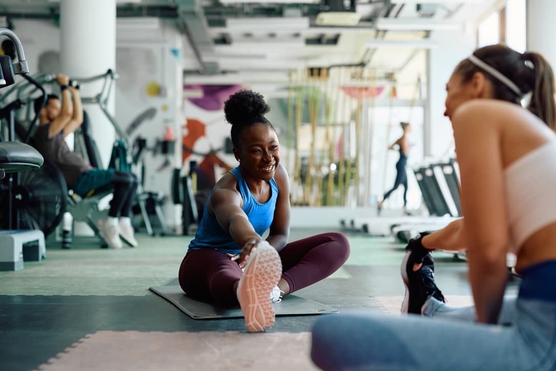 Two women stretching in the gym