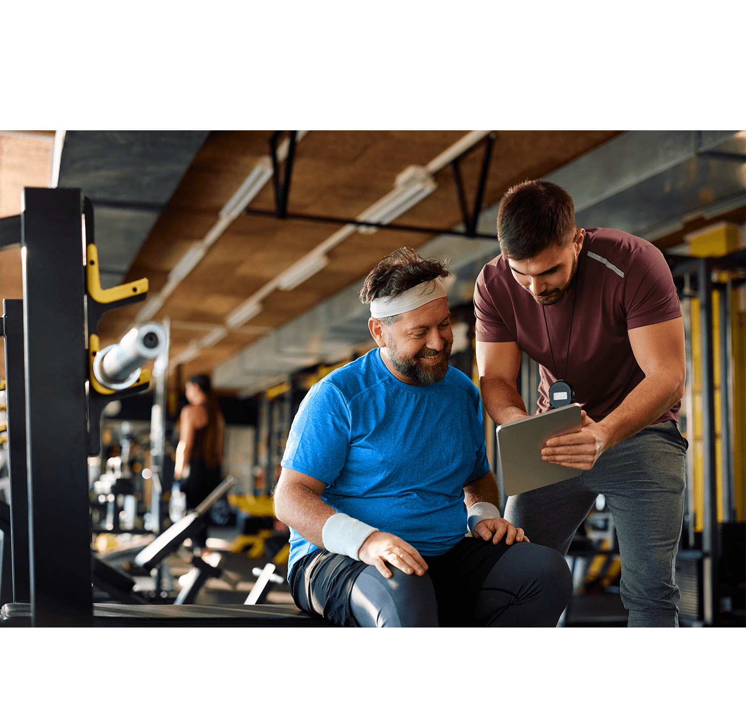 Medical fitness director reviewing member engagement data on a Club Automation dashboard with a member nearby.